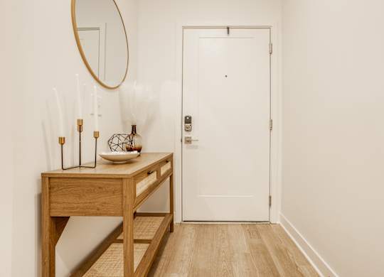 A white door is in a hallway with a wooden table and a mirror at Upper Vue Flats, Dublin