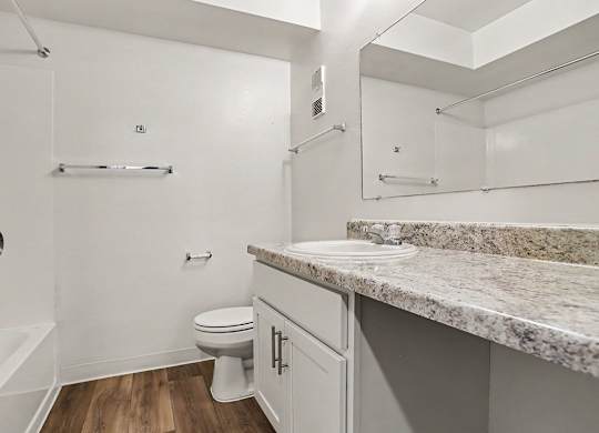 A white bathroom with a large counter top and a toilet at Walnut Trail Apartments, Michigan