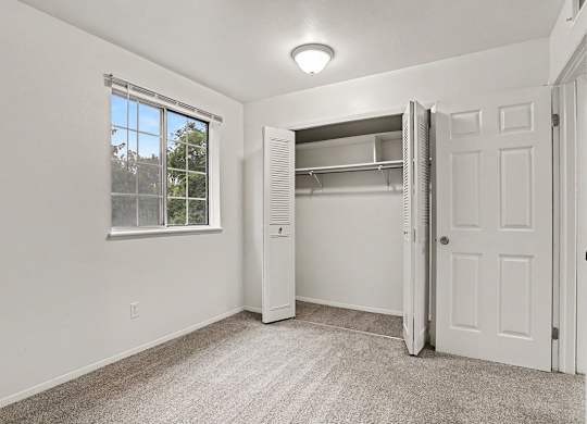 A white bedroom with a window and a closet at Walnut Trail Apartments, Michigan