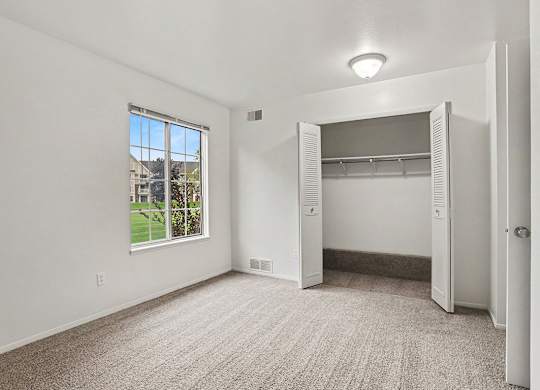 A spacious bedroom with a large window and a closet at Walnut Trail Apartments, Michigan