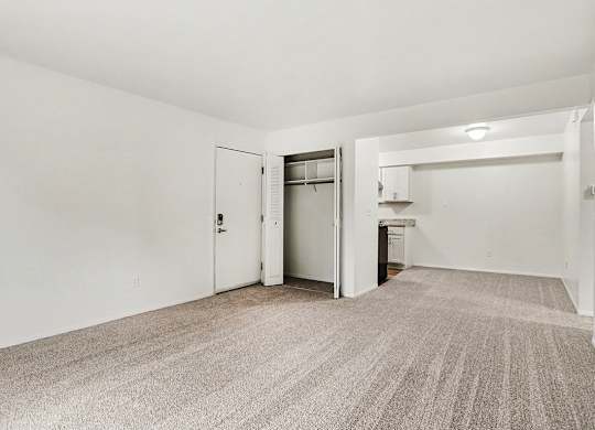 A living and dining room with a carpeted floor and a closet at Walnut Trail Apartments, Michigan