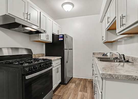 A kitchen with stainless steel appliances and white shaker cabinets at Walnut Trail Apartments, Michigan