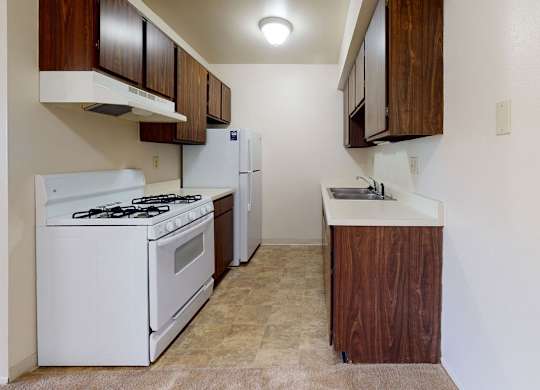 A kitchen with white appliances and brown cabinets at Walnut Trail Apartments, Michigan