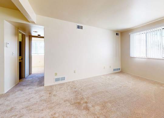 A large garden style living room with a window and carpeted floor at Walnut Trail Apartments, Michigan