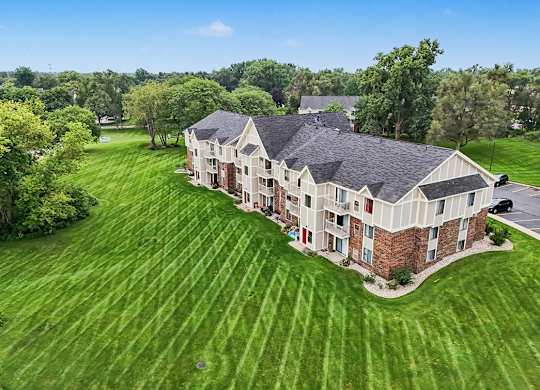 A large building with a green lawn in front of it at Walnut Trail Apartments, Michigan