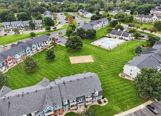 A bird's eye view of a residential area with apartment buildings, a swimming pool, and a parking lot at Walnut Trail Apartments, Michigan