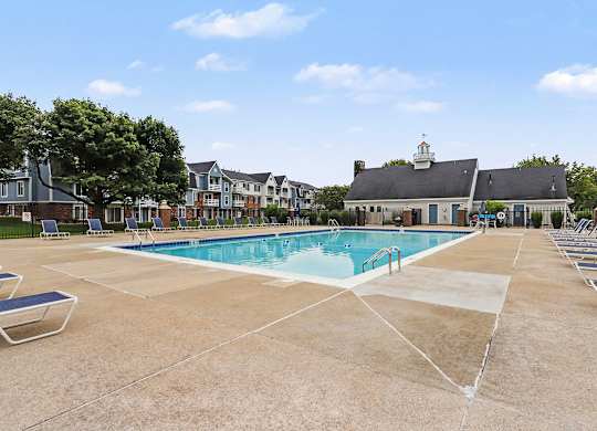 A large swimming pool surrounded by lounge chairs and a building in the background at Walnut Trail Apartments, Michigan