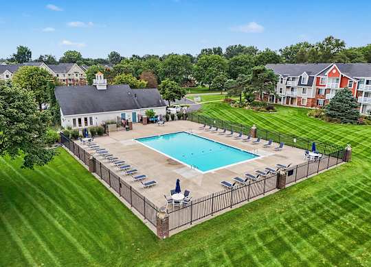 A pool surrounded by a sundeck and lounge chairs at Walnut Trail Apartments, Michigan