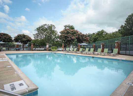 A large swimming pool surrounded by a fence and lounge chairs at WaterFront Apartments, Virginia Beach, 23453