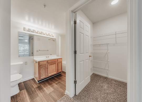 A bathroom with a white tub and sink, a wooden cabinet, and a white door at WaterFront Apartments, Virginia Beach, 23453