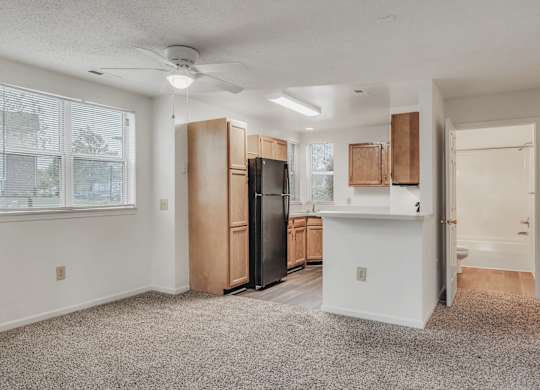A spacious kitchen with wooden cabinets and a black refrigerator at WaterFront Apartments, Virginia Beach, 23453