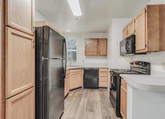 A kitchen with wooden cabinets and black appliances at WaterFront Apartments, Virginia Beach, 23453