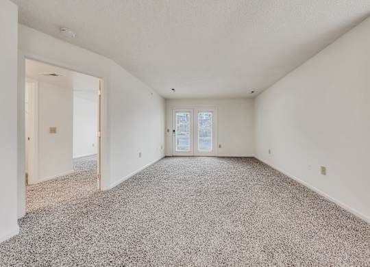 A spacious room with a carpeted floor and a door at the end at WaterFront Apartments, Virginia Beach, 23453
