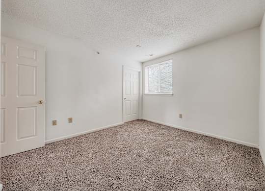 A room with a carpeted floor and a door on the left side at WaterFront Apartments, Virginia Beach, 23453