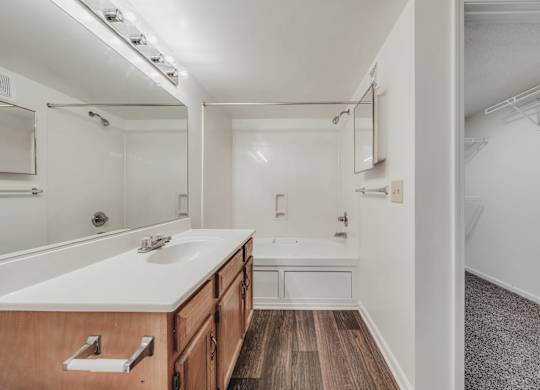 A bathroom with a wooden vanity and a white countertop at WaterFront Apartments, Virginia Beach, 23453