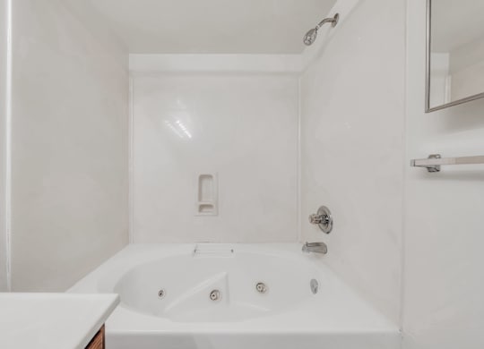 A white bathroom with a tub and a mirror at WaterFront Apartments, Virginia Beach, 23453