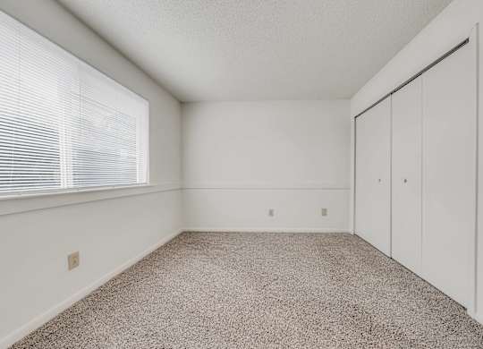 A room with a carpeted floor and a window with blinds at WaterFront Apartments, Virginia Beach, 23453