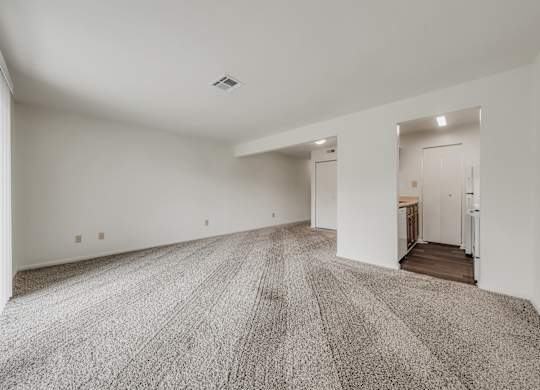 A large, empty room with a carpeted floor and white walls at WaterFront Apartments, Virginia Beach, 23453
