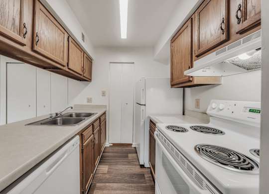 A kitchen with white appliances and wooden cabinets at WaterFront Apartments, Virginia Beach, 23453