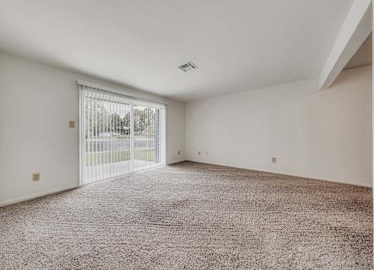 A room with a carpeted floor and a sliding glass door at WaterFront Apartments, Virginia Beach, 23453
