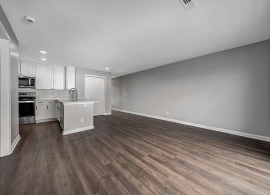 the living room and kitchen of an apartment with wood flooring and white cabinets at WaterFront Apartments, Virginia