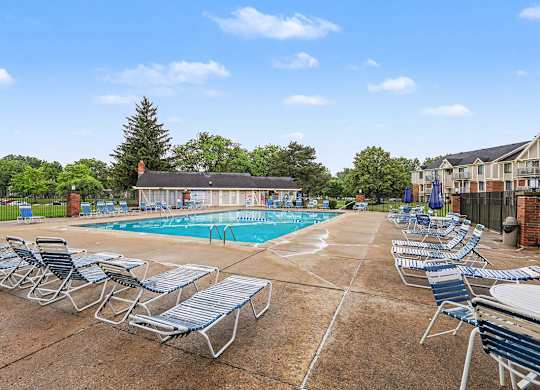 A pool surrounded by chairs and a large sundeck at Waverly Park Apartments, Lansing