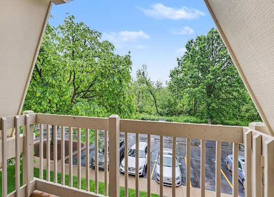 A balcony with a view of a parking lot and trees at Waverly Park Apartments, Lansing
