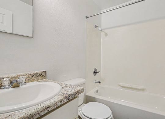 A white toilet sits next to a sink in a bathroom at Waverly Park Apartments, Lansing