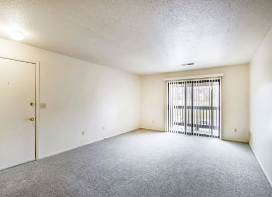 large living room with a sliding glass door to a balcony at West Wind Apartments in Fort Wayne, IN