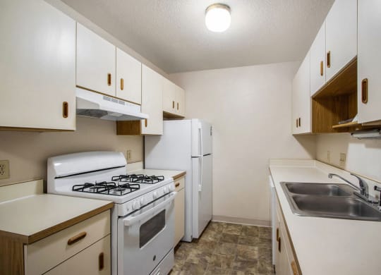 kitchen with a gas stove, refrigerator and sink at West Wind Apartments in Fort Wayne, IN