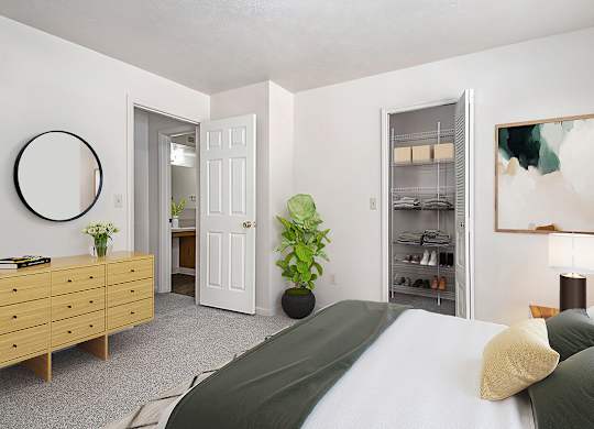 A bedroom with a bed, dresser, and a walk-in closet with wardrobe organizers at West Hampton Park Apartments in Elkhorn, NE 68022