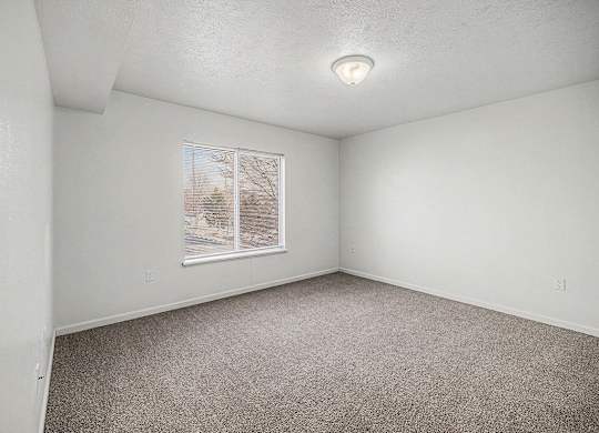 A bedroom with a large window and carpeted floor  at West Hampton Park Apartment Homes, Nebraska, 68022