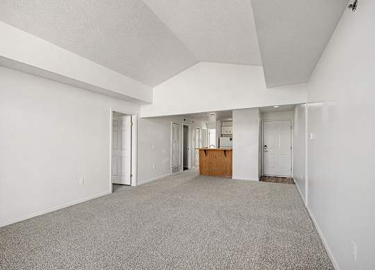 A spacious empty dining room with a carpeted floor and cathedral ceiling  at West Hampton Park Apartment Homes, Nebraska, 68022