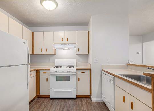 A kitchen with white appliances and a breakfast bar at West Hampton Park Apartments in Elkhorn, NE 68022