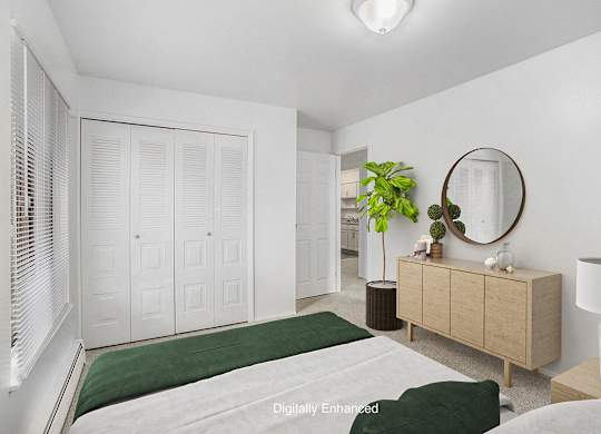 An upgraded bedroom with a green bedspread and a large closet at Wingate Apartments, Michigan