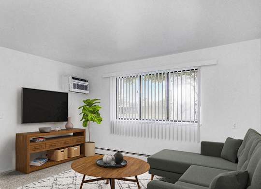 A garden style living room with a grey couch, a wooden coffee table, and a television at Wingate Apartments, Michigan
