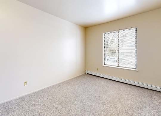 A large bedroom with a window and carpeted floor at Wood Creek Apartments, Kenosha, WI, 53144