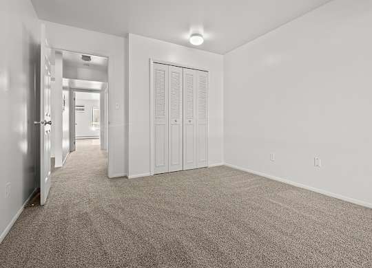A large bedroom with a carpeted floor and a closet at Wood Creek Apartments, Kenosha