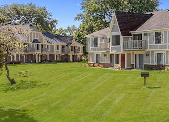 A large grassy area behind a building with a picnic table and grill at Wood Creek Apartments, Wisconsin
