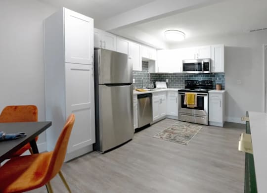 A kitchen with a refrigerator, oven, and sink.