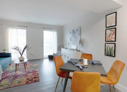 A dining room with a table set for two and a sofa in the background.