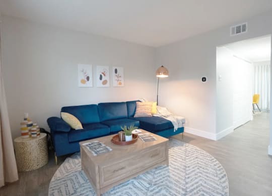 A living room with a blue couch and a wooden coffee table.
