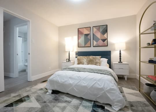 A bedroom with a large bed and a rug on the floor.