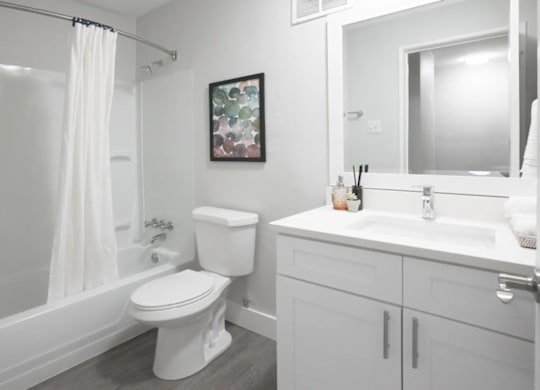 A white bathroom with a toilet, sink, and shower.