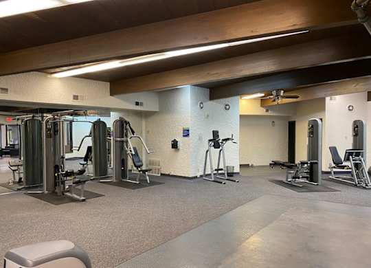 A gym with a variety of equipment including treadmills, weights, and exercise machines.