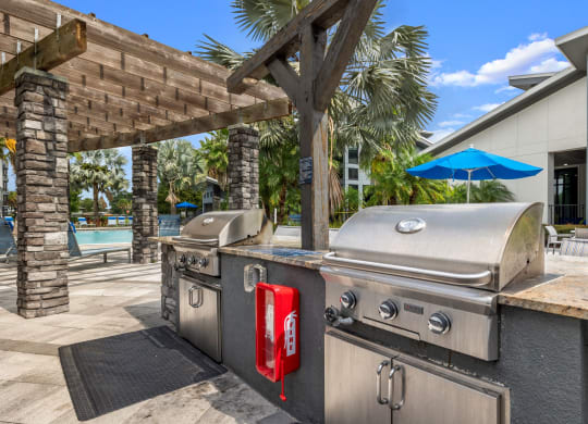 a backyard with two stainless steel barbecue grills and a picnic table