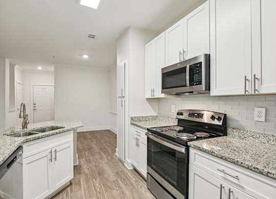 A renovated kitchen with white cabinets, granite countertops through out and stainless steel appliances