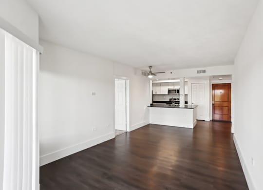 A spacious living room with faux wooden floors and white walls.