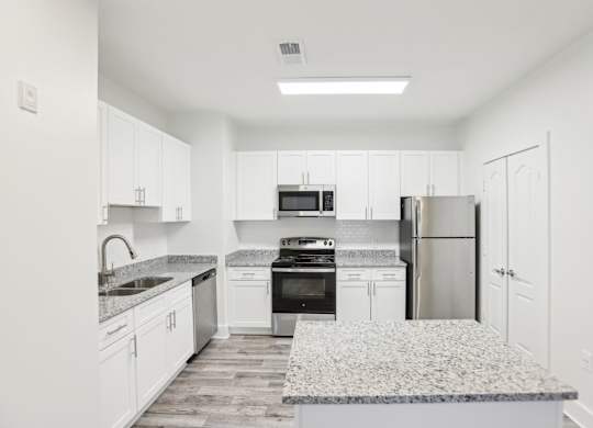 A kitchen with white cabinets and a granite countertop.