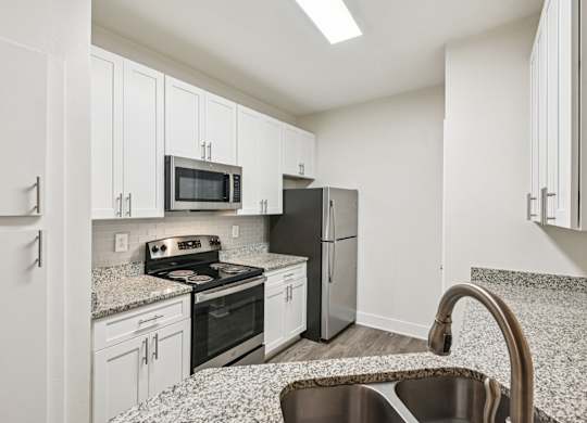 A renovated kitchen with white cabinets, granite countertops through out and stainless steel appliances